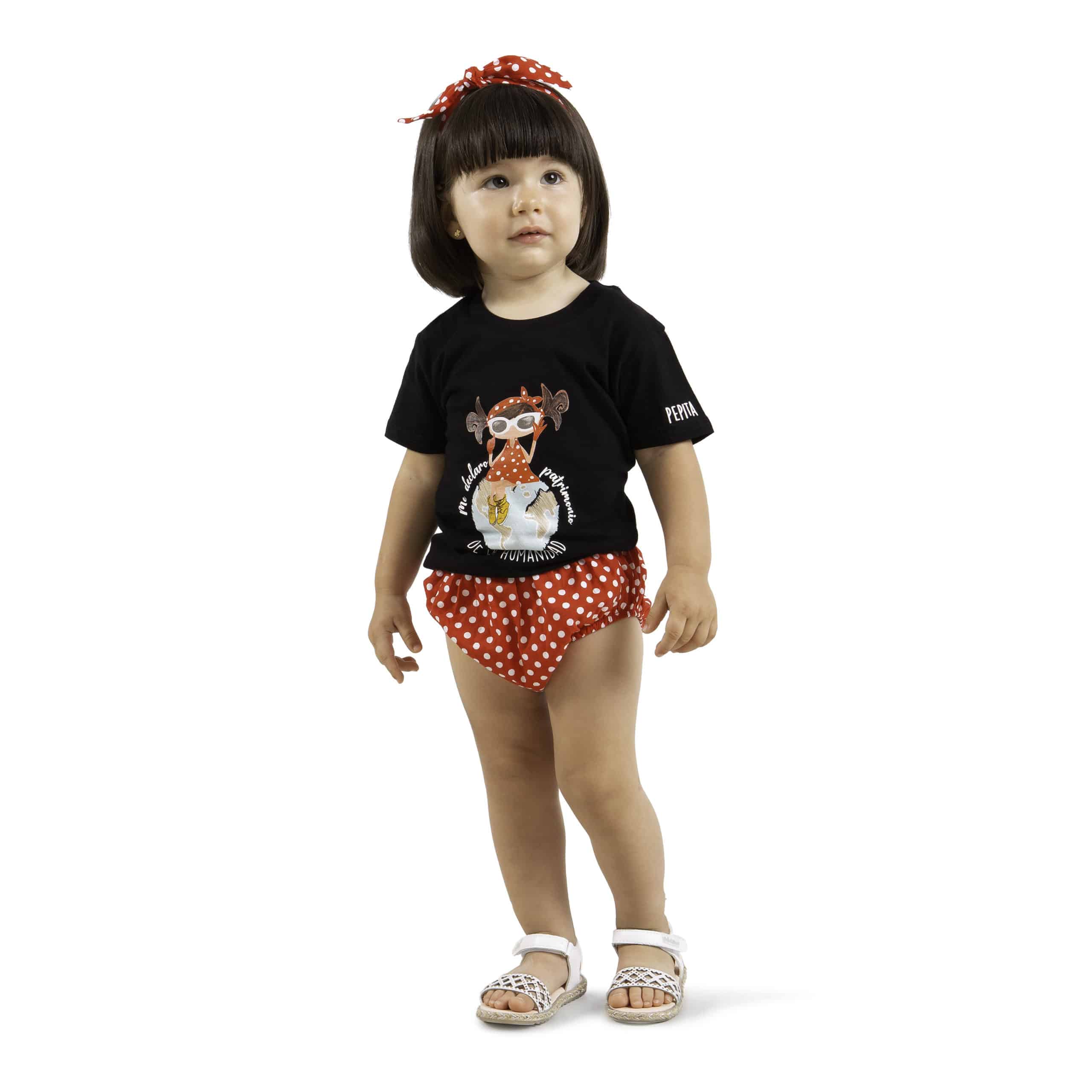 Camiseta de algodón orgánico de la marca Pepita Viajera en color negro para aquellos que se declaran Patrimonio de la humanidad. Vista puesta en modelo chica bebé